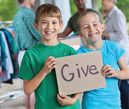 Kids holding a sign that says Give